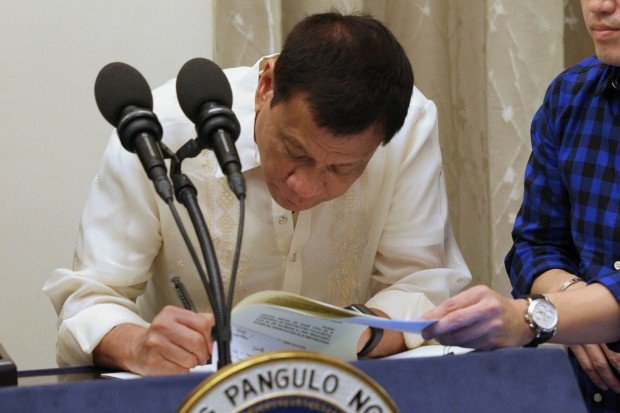 Photo of former president Rodrigo Duterte of the Philippines signing his executive
                order on freedom of information.